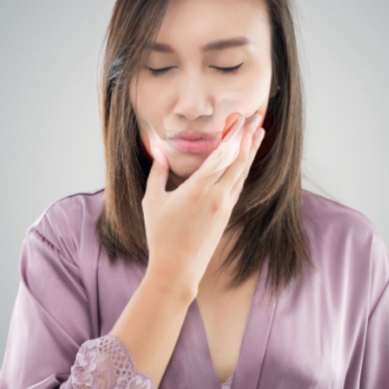 Woman holding her aching jaw