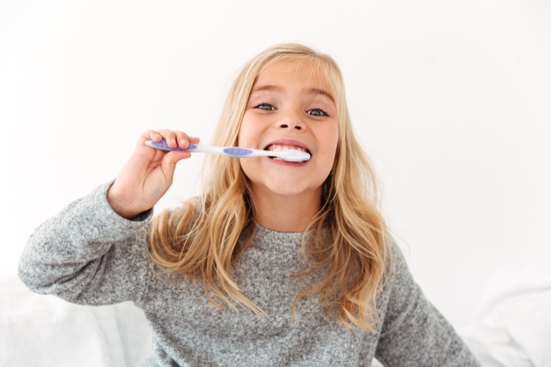 Girl laughing while brushing her teeth